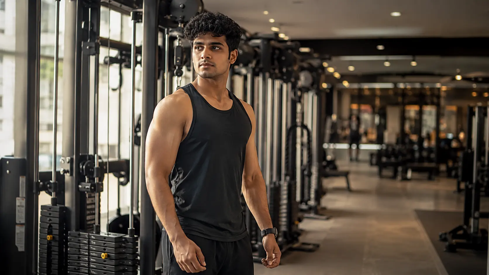 A beginner standing confidently in a gym next to a row of resistance machines, about to start a workout