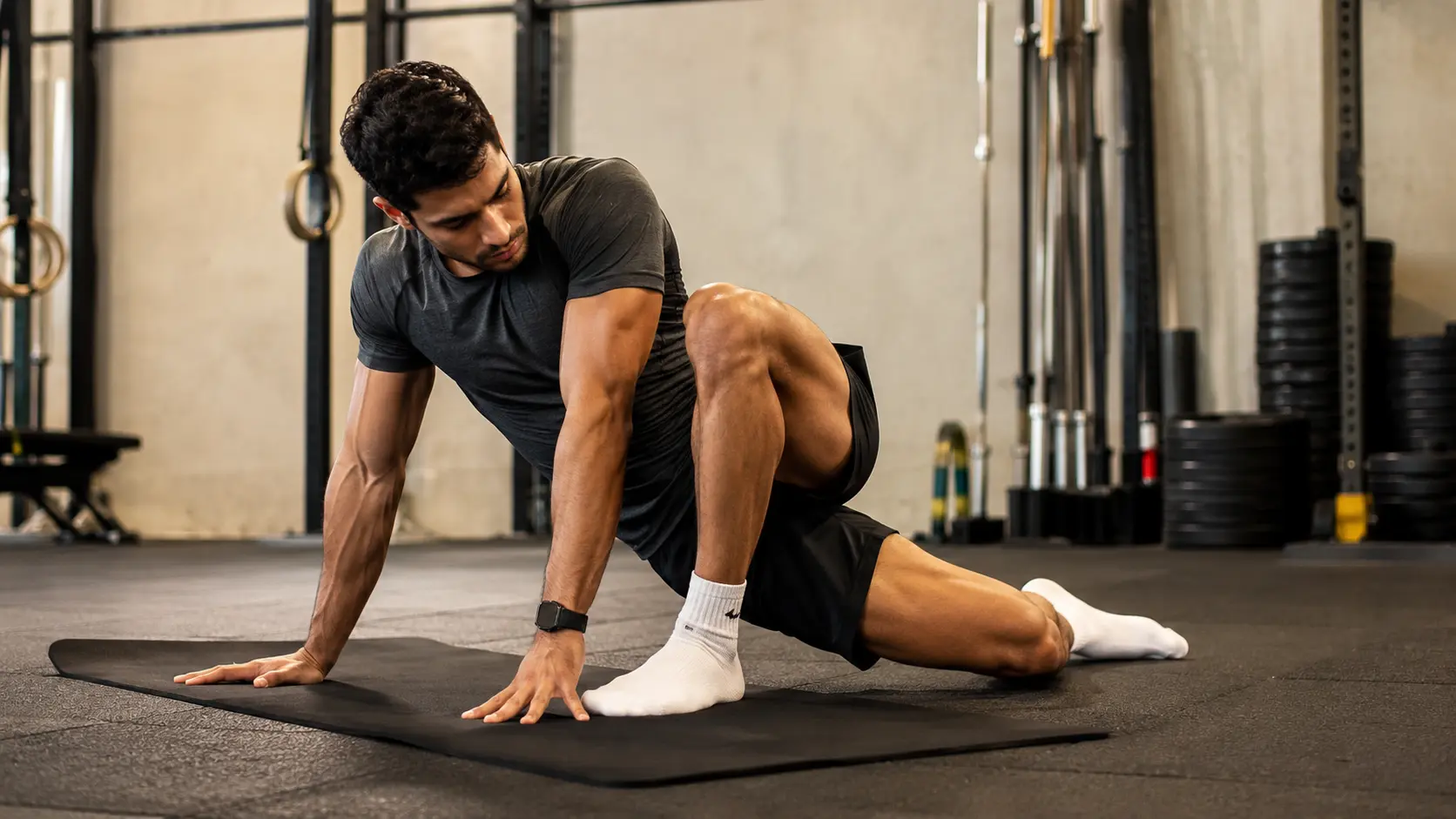 A person performing a controlled hip mobility exercise on a gym mat, actively rotating through a deep range of motion